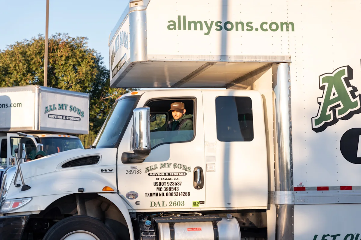 Professional movers from All My Sons drive a moving truck carrying household goods for a move.