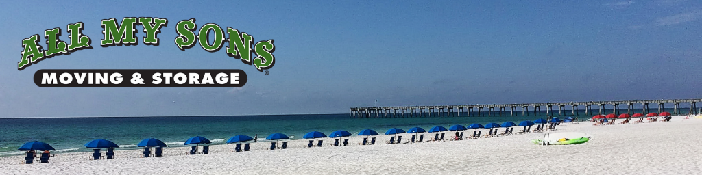 white sands lined by beach chairs with a bridge in the distance