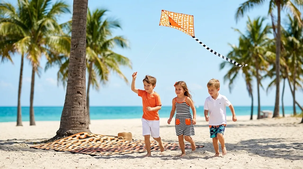 Professional lifestyle photography of happy young children running and playing with a bright orange kite at a sunny Miami bea