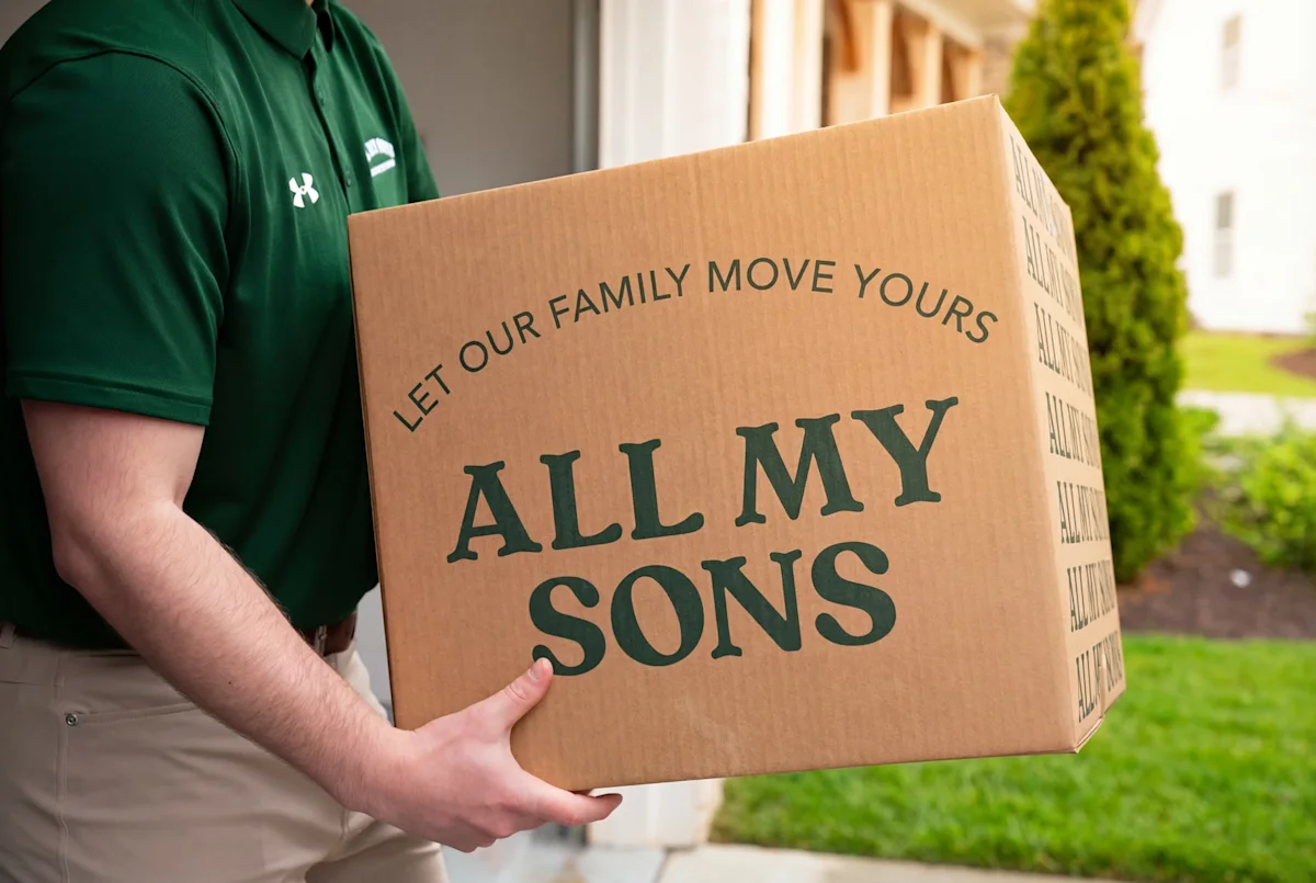 An All My Sons mover takes a moving box out to the truck on a hot summer move.