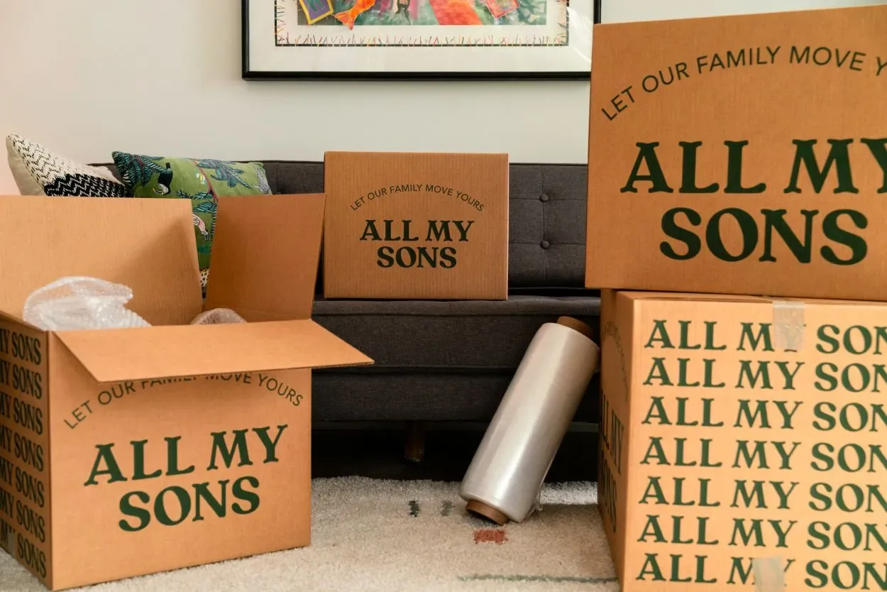 An All My Sons moving box sits on a couch while other boxes are packed. 