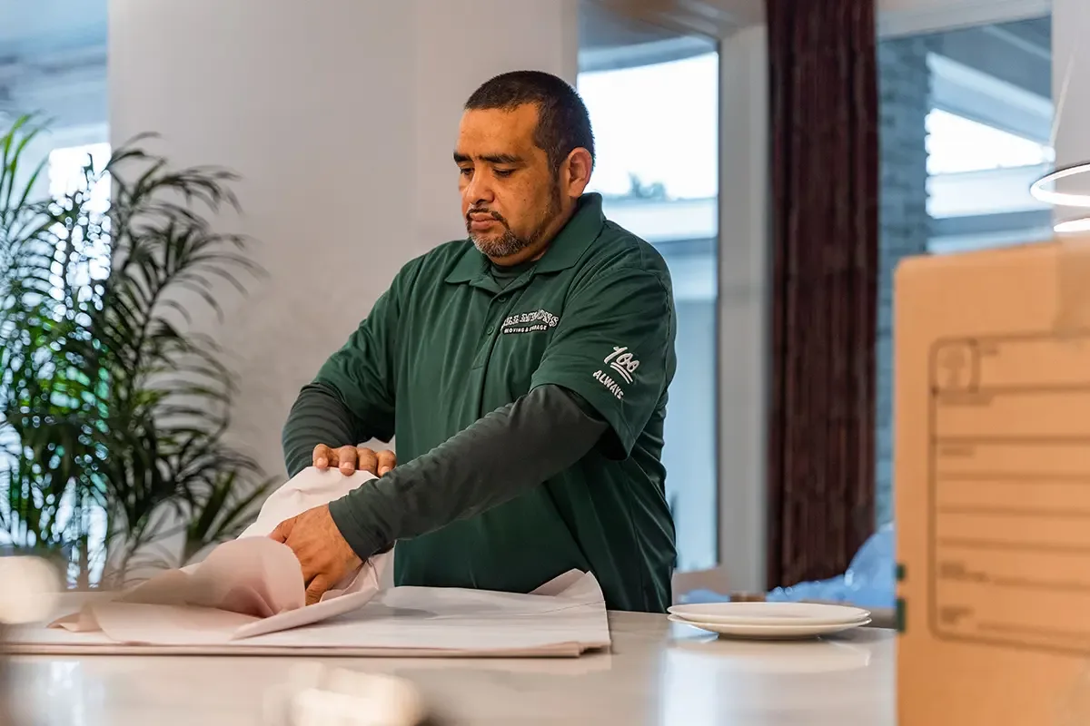 Professional packers from All My Sons Moving and Storage wrap plates for a household move.