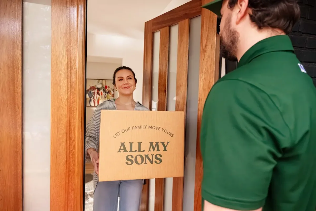 A woman prepares for a move into a significant other's place by giving a box to an All My Sons team member.