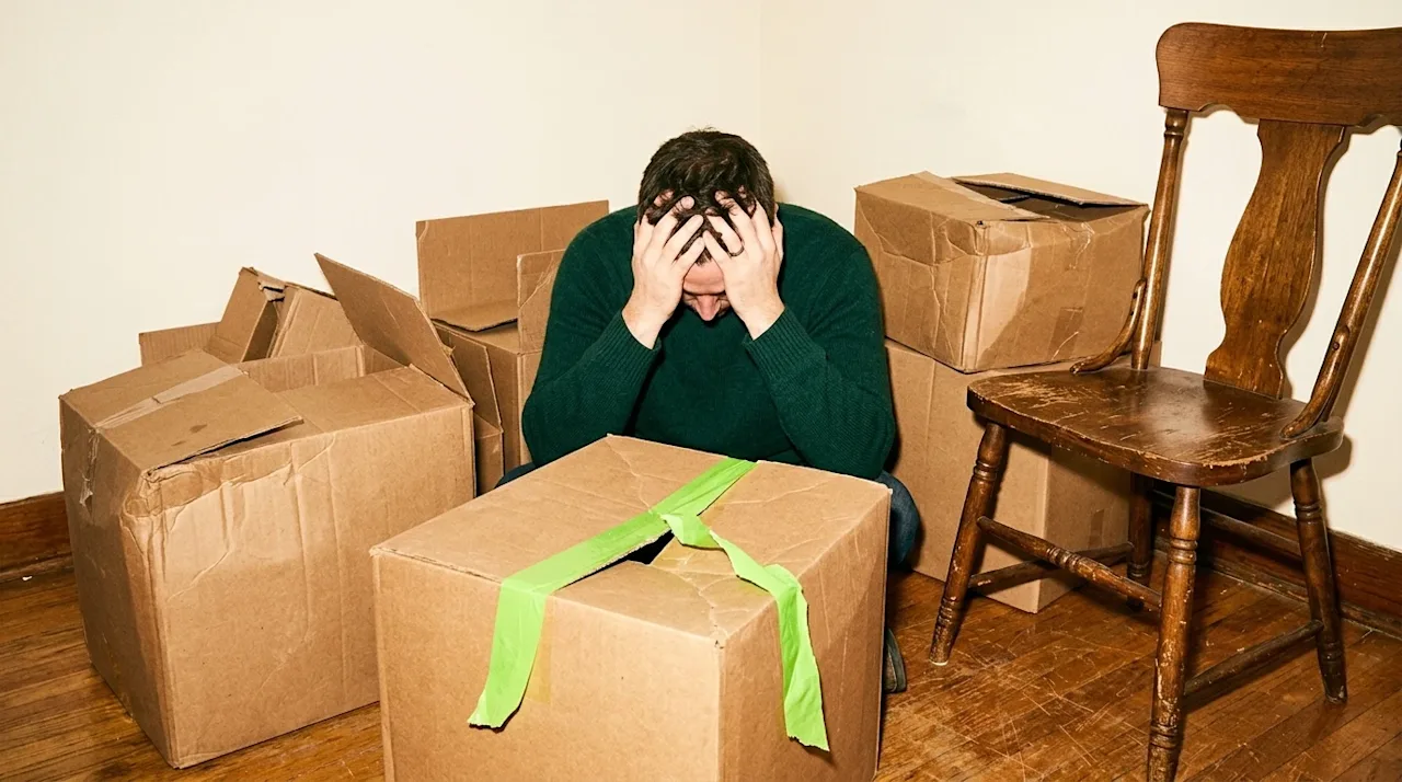 Documentary-style 35mm film photography of a highly stressed homeowner dealing with a moving disaster, representing the conse