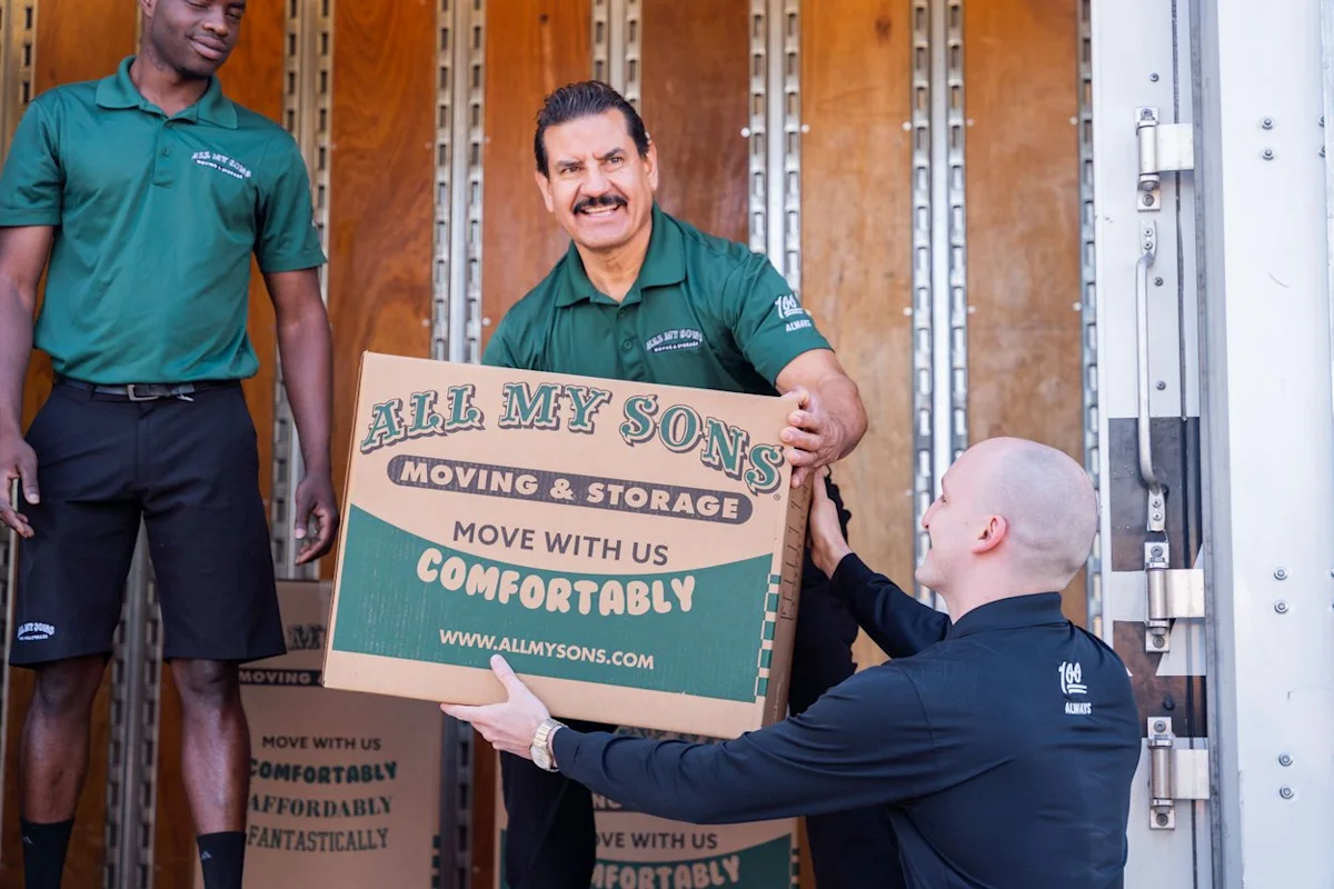 Professional movers from All My Sons Moving and Storage transport a moving box packed with records.