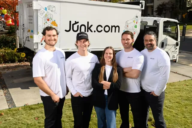 Professional Junk.com Removal crew in white shirts standing with their truck ready for residential service.