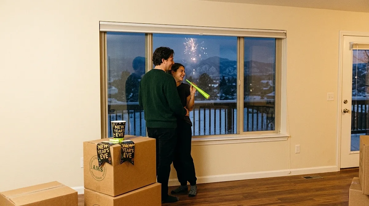 A candid, authentic lifestyle photograph of a joyful couple celebrating New Year's Eve in their newly moved-in home in Colora