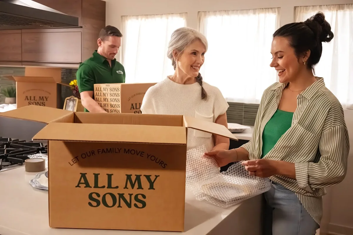 A senior mover with an adult daughter pack an All My Sons box for transportation to storage.