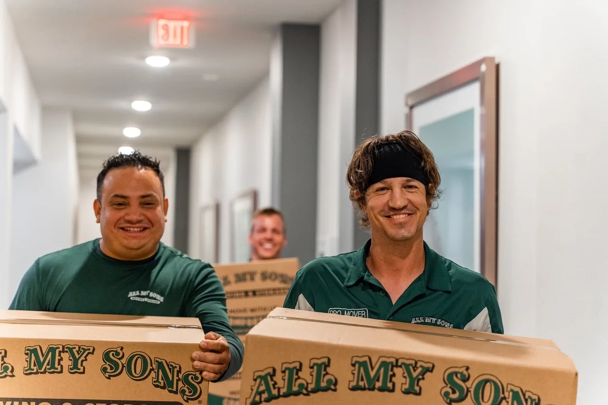 Professional movers from All My Sons Moving and Storage move boxes into a college dorm.