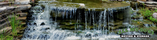 A crick and small waterfall leading towards woodlands lake