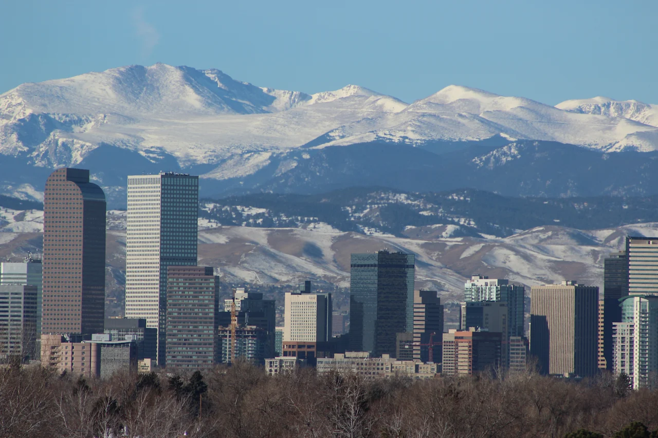 Downtown Denver skyline with rocky mountains in background. 