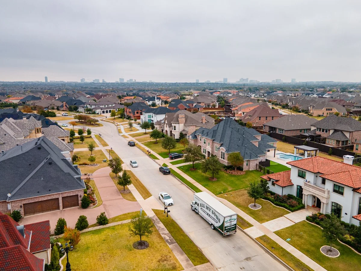 All My Sons moving truck on the curb of a well-manicured lawn with beautiful homes on either side of the street.