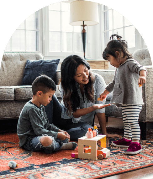 Mother and her two children playing with toys in the living room on the rug