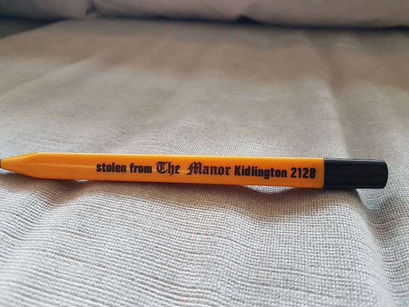 A yellow pen on a beige surface with the text 'stolen from The Manor Kiddlington 2120'  