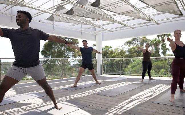 Four people practising yoga outside