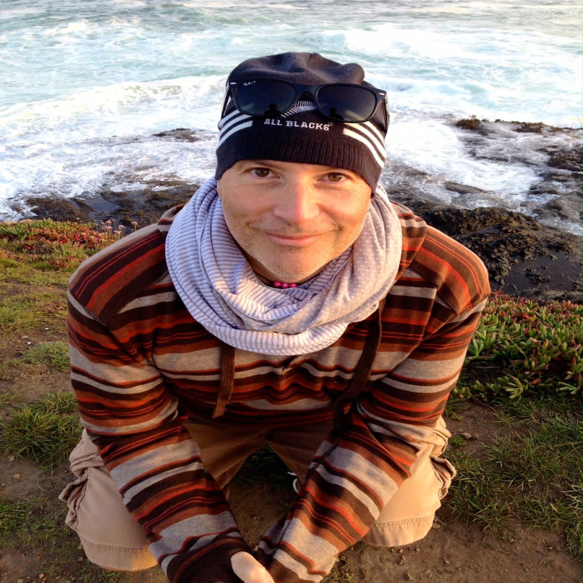 author Rick Macpherson smiles up at the camera in front of a beach