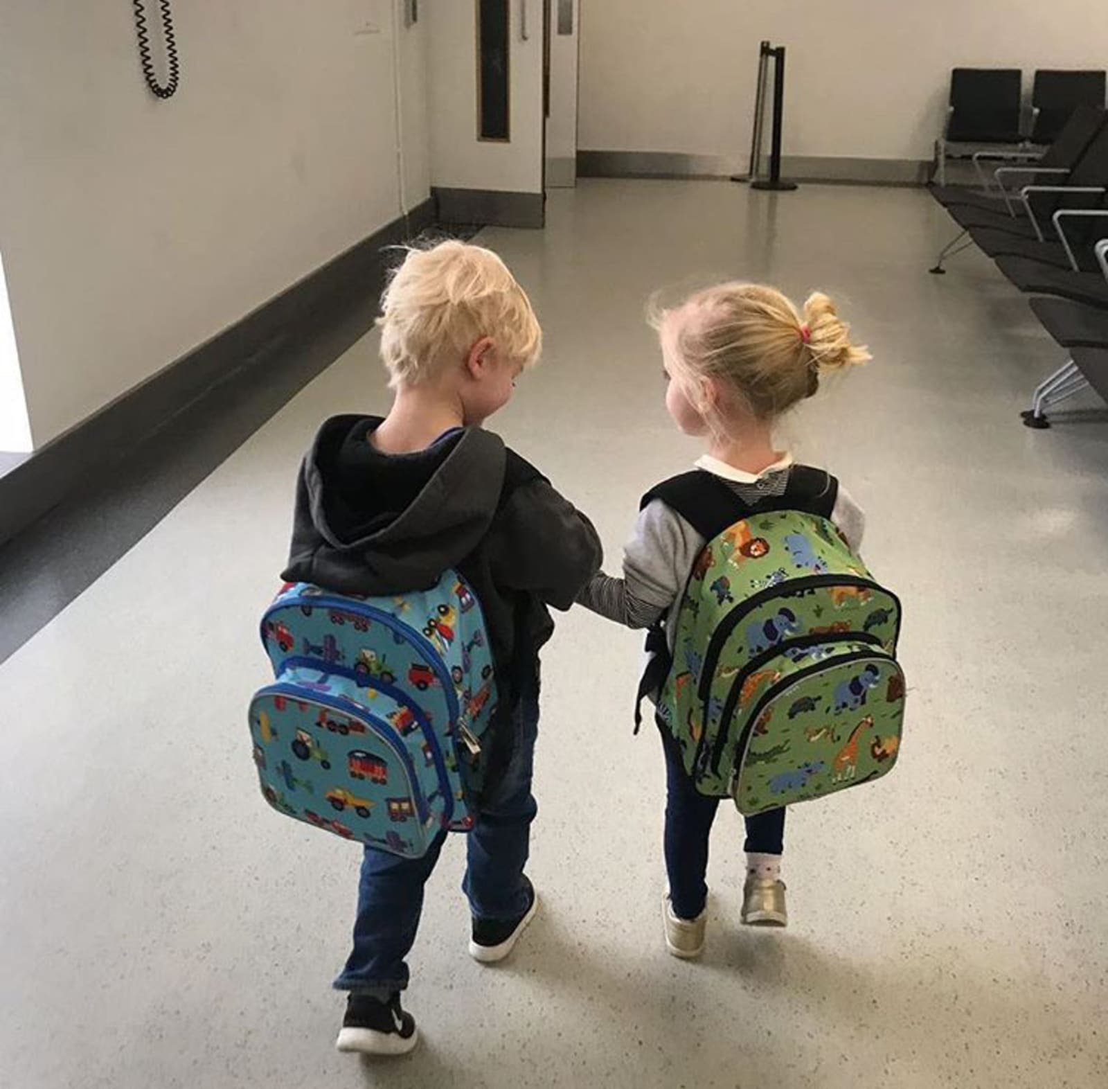 Holly's twin children with backpacks holding hands