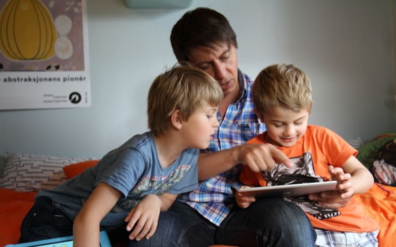 A man reading a book with two young boys
