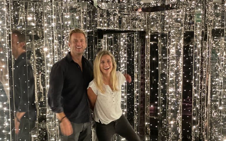 Holly Branson and Freddie Andrewes smile in a lit up mirror room onboard Virgin Voyages ship, Scarlet Lady