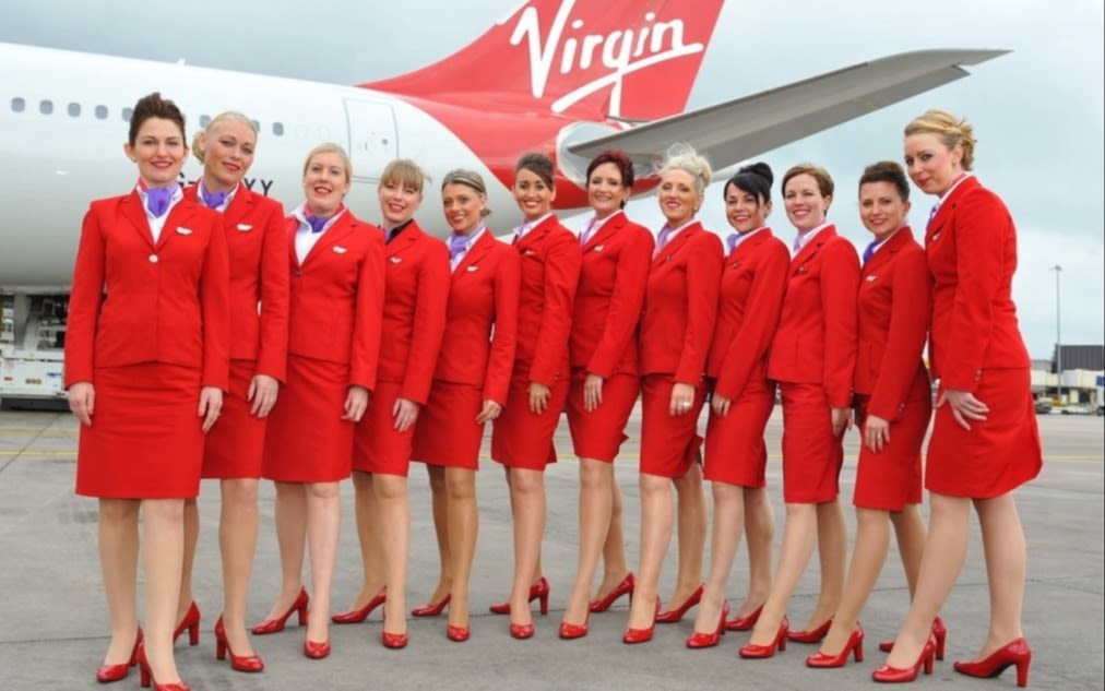 12 Virgin Atlantic cabin crew members wear the Virgin Atlantic uniform designed by John Rocha