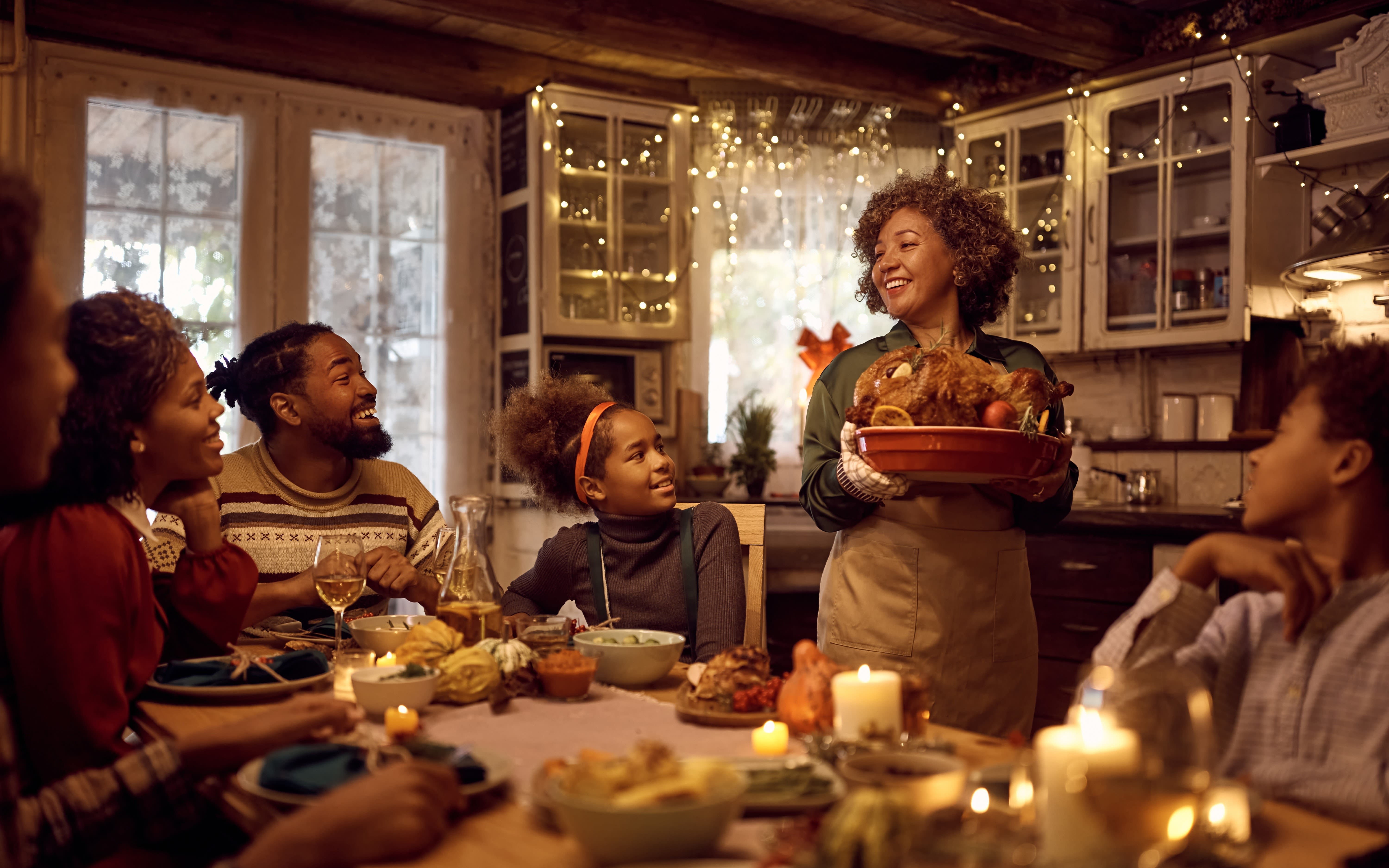 An image of a woman bringing food to the table at Thanksgiving. 