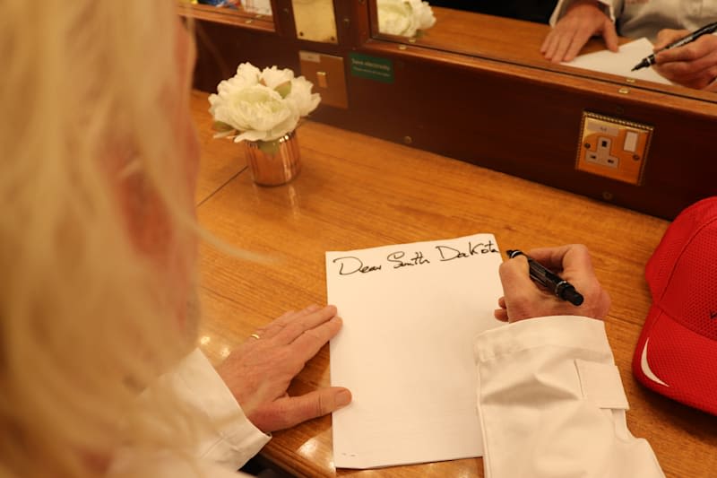 Richard Branson writing a letter. The letter says 'Dear South Dakota'