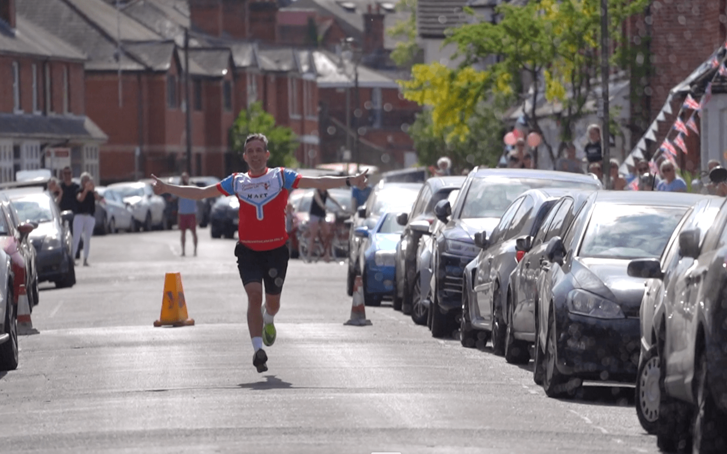 A marathon runner runs towards the camera with arms raised