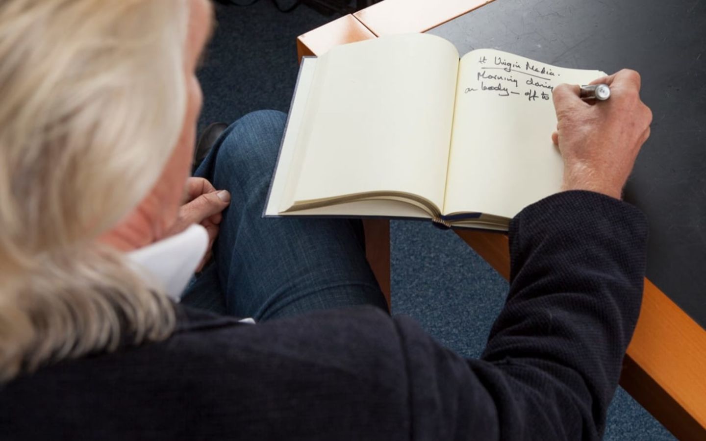 A view from above of Richard Branson writing in a notebook