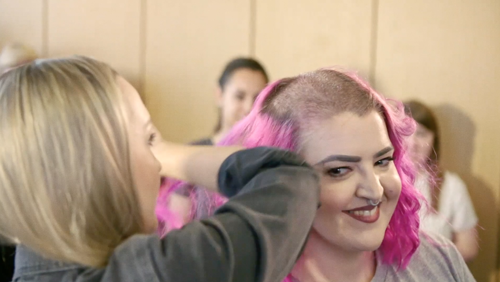 A woman with pink hair has it shaved off for charity