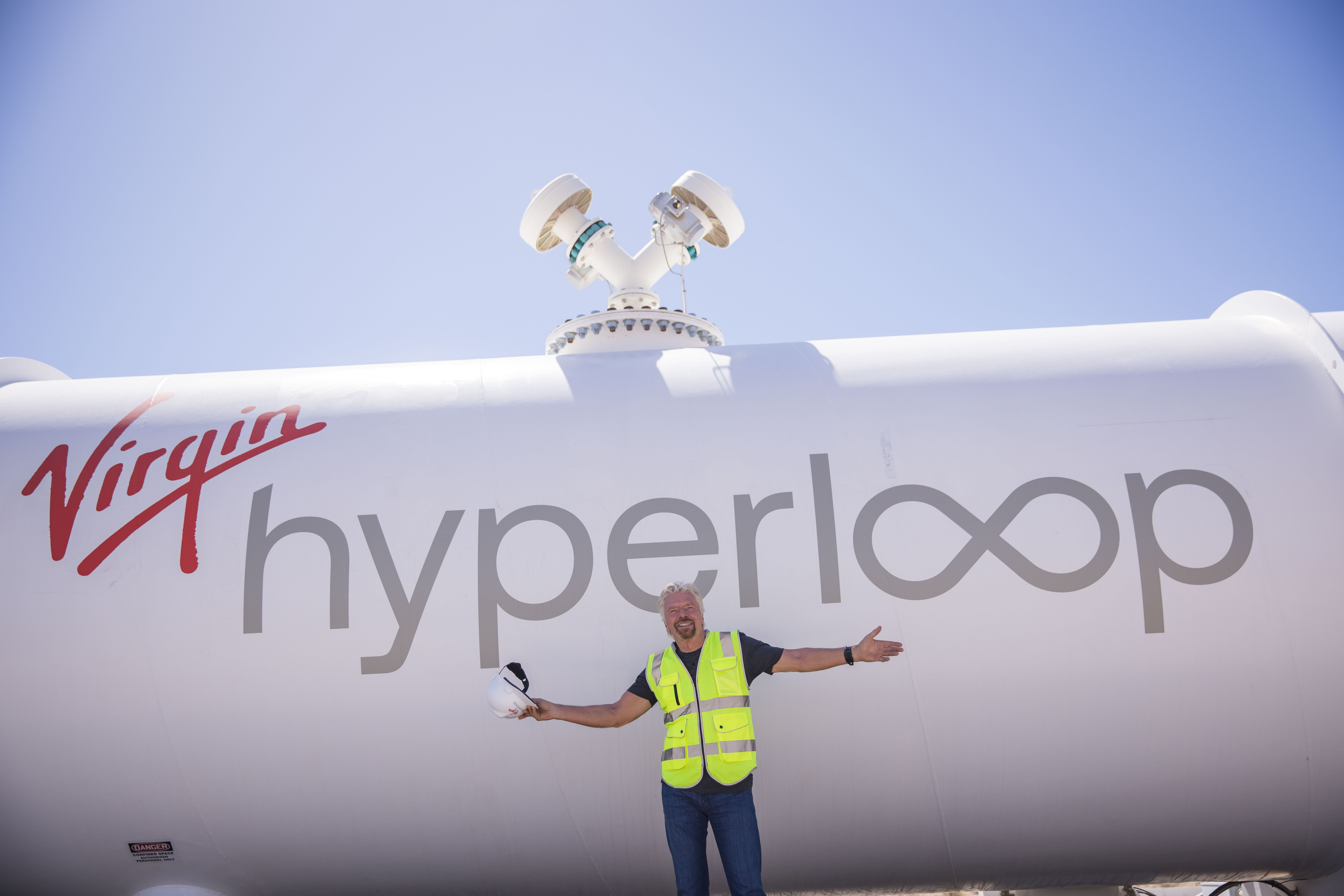 Richard Branson smiling in front of Virgin Hyperloop's XP-2 vehicle