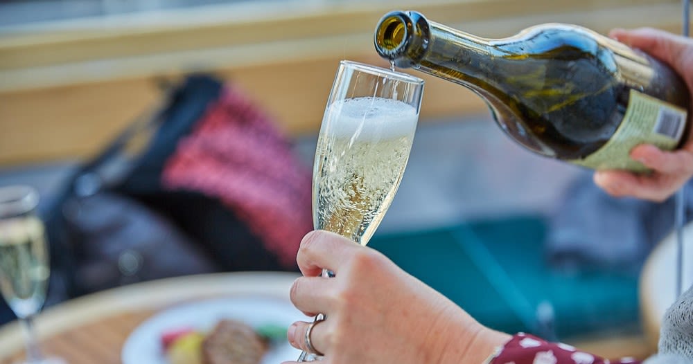 A person pouring sparkling wine into a glass