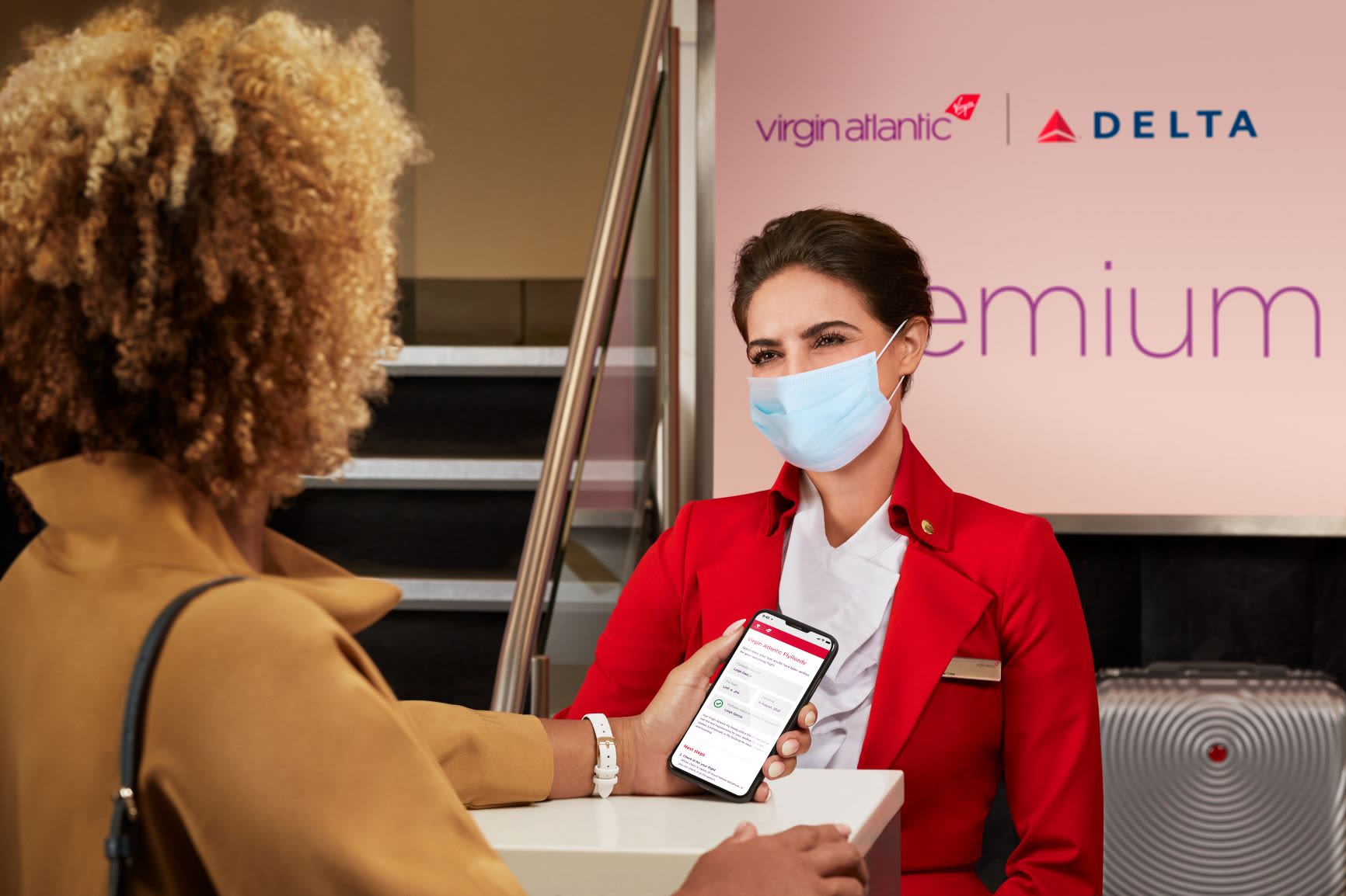 A woman showing her phone at check-in to a Virgin Atlantic cabin crew member