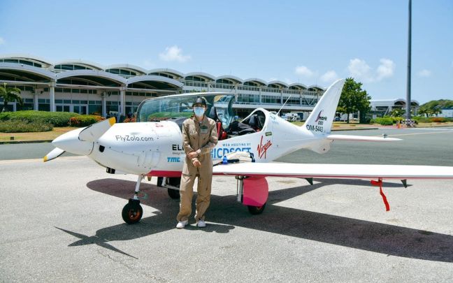 Zara Rutherford stands next to her Shark plane at an airport in the BVI