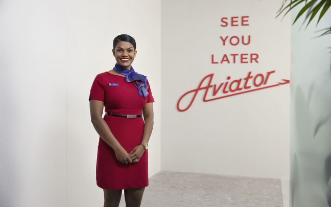 A member of Virgin Australia cabin crew poses in front of a sign that reads "See you later aviator"