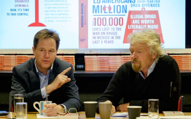 Richard Branson sitting next to Nick Clegg at a table