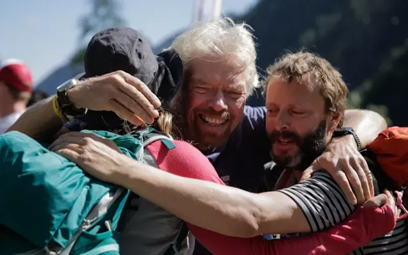 Richard Branson hugging a man and woman during the Strive Challenge