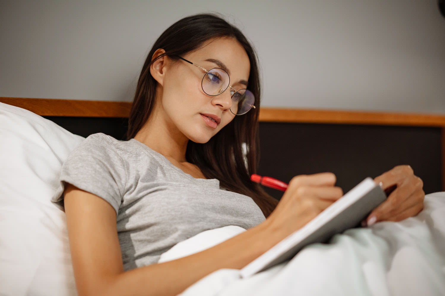 A woman sitting in bed, writing in a journal