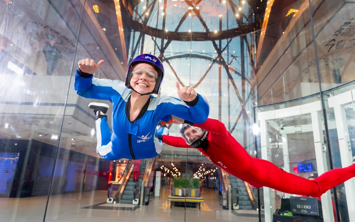 Image of happy woman indoor skydiving at iFly with an instructor.