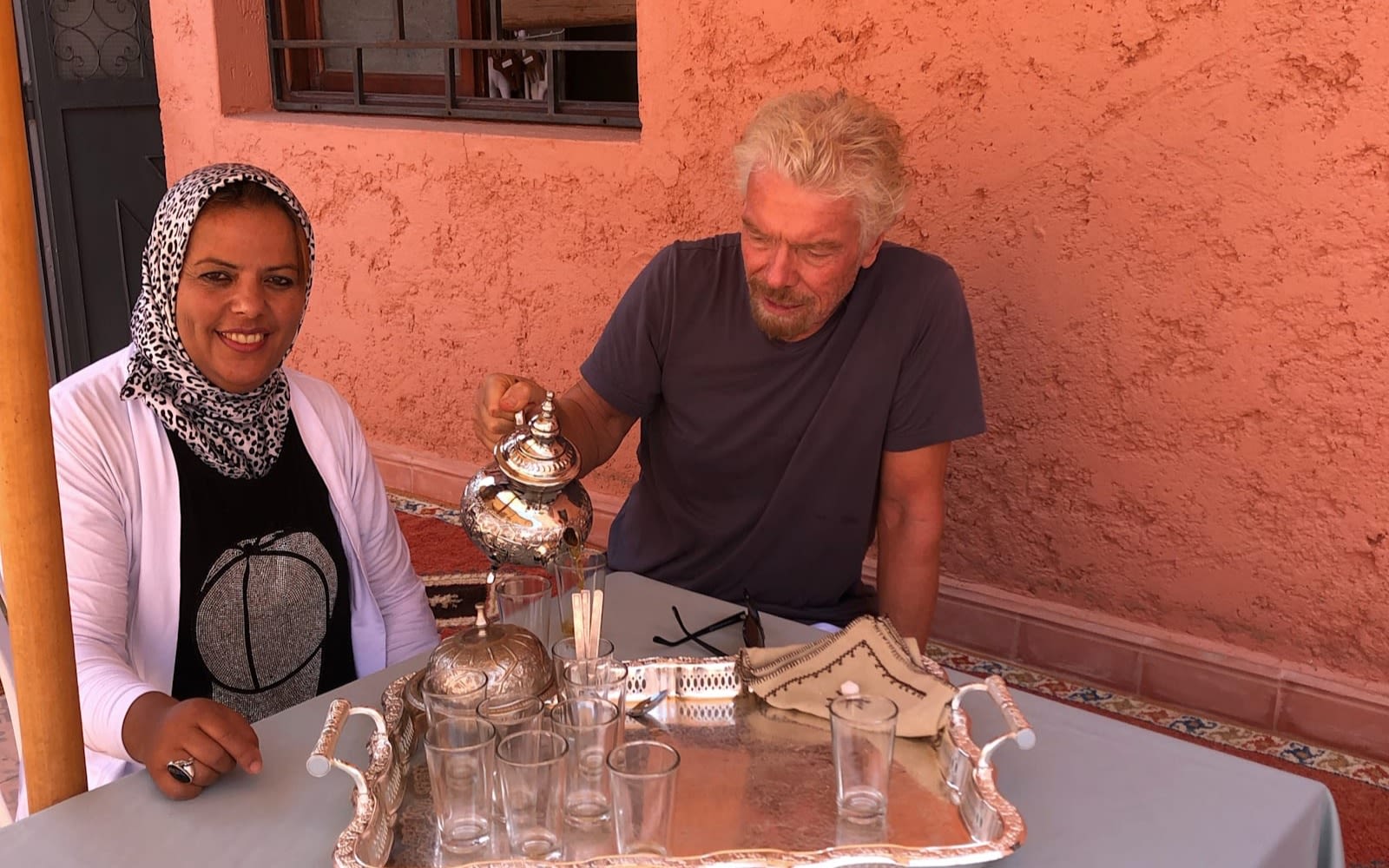 Richard Branson pouring tea, sitting next to a woman
