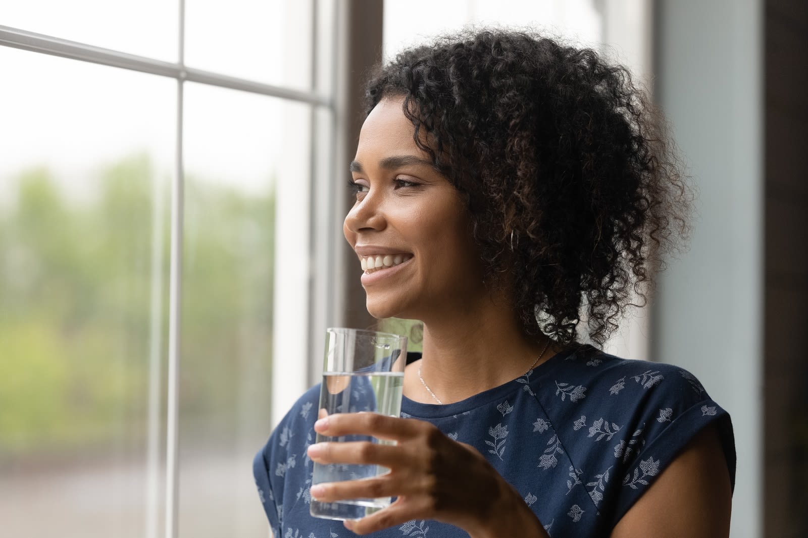 Woman drinking water by window