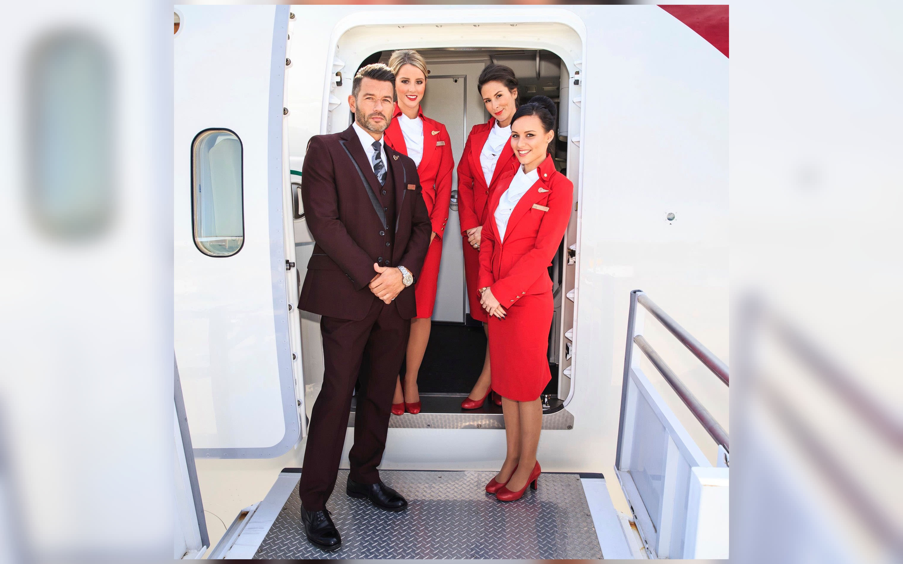 Four Virgin Atlantic cabin crew members standing at the door of a plane
