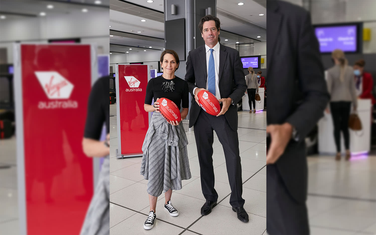 Virgin Australia CEO Jayne Hrdlicka and AFL CEO Gillon McLachlan holding footballs in the departure hall at Melbourne Airport