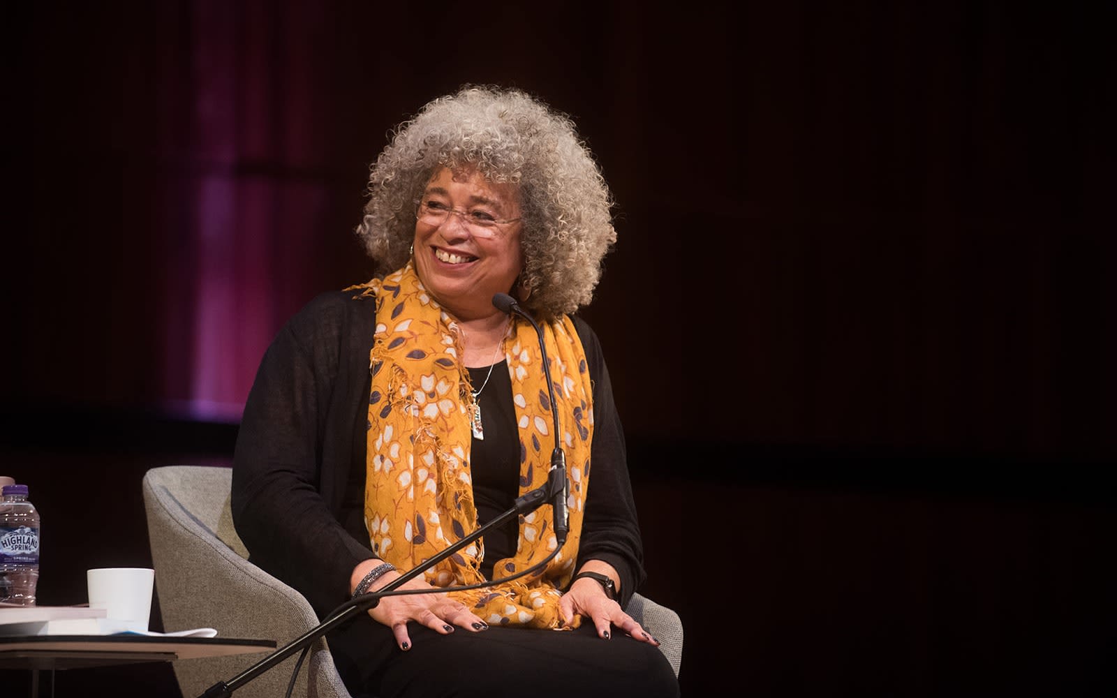 Angela Davis sitting on a stage smiling