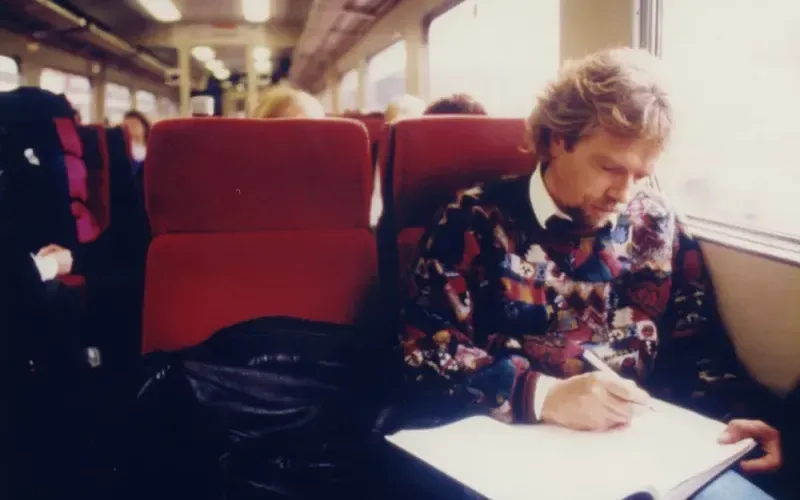 Richard Branson writes in a notebook while travelling on a train