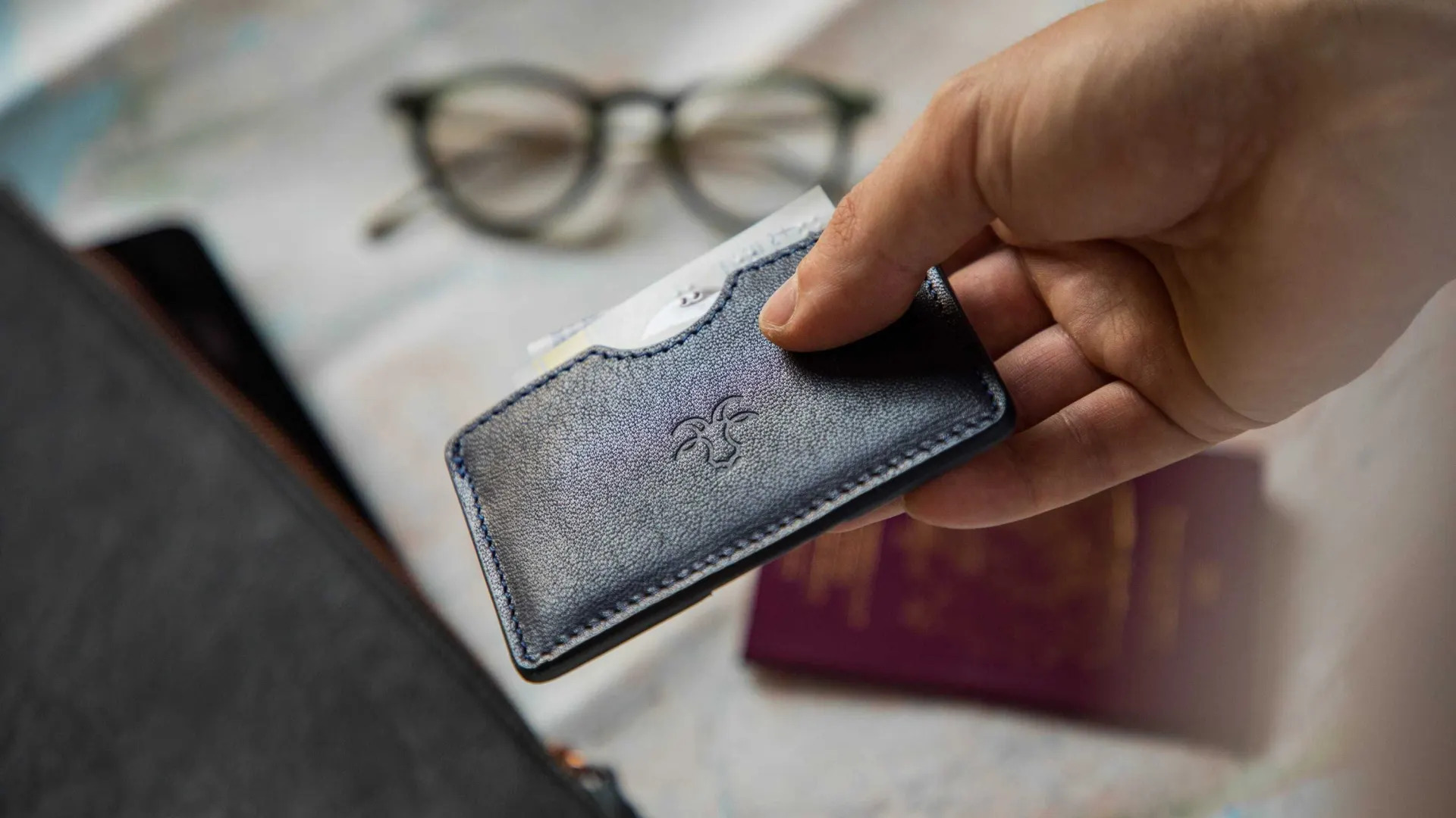A person holding a navy blue Billy Tannery leather cardholder wallet