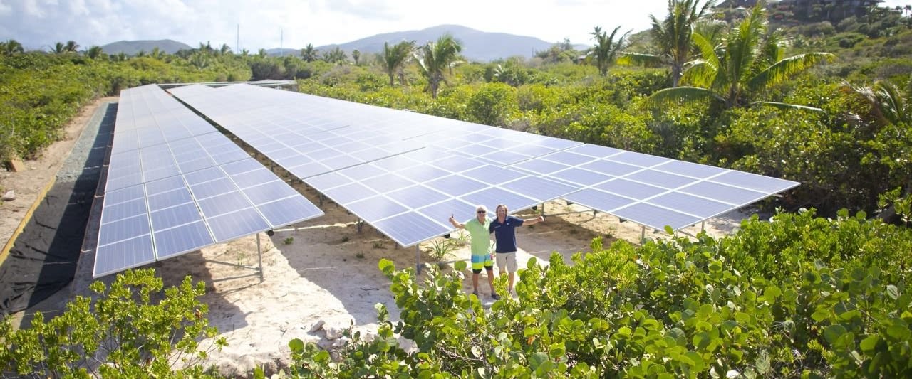 Richard Branson stands in a solar panel field with his thumbs up