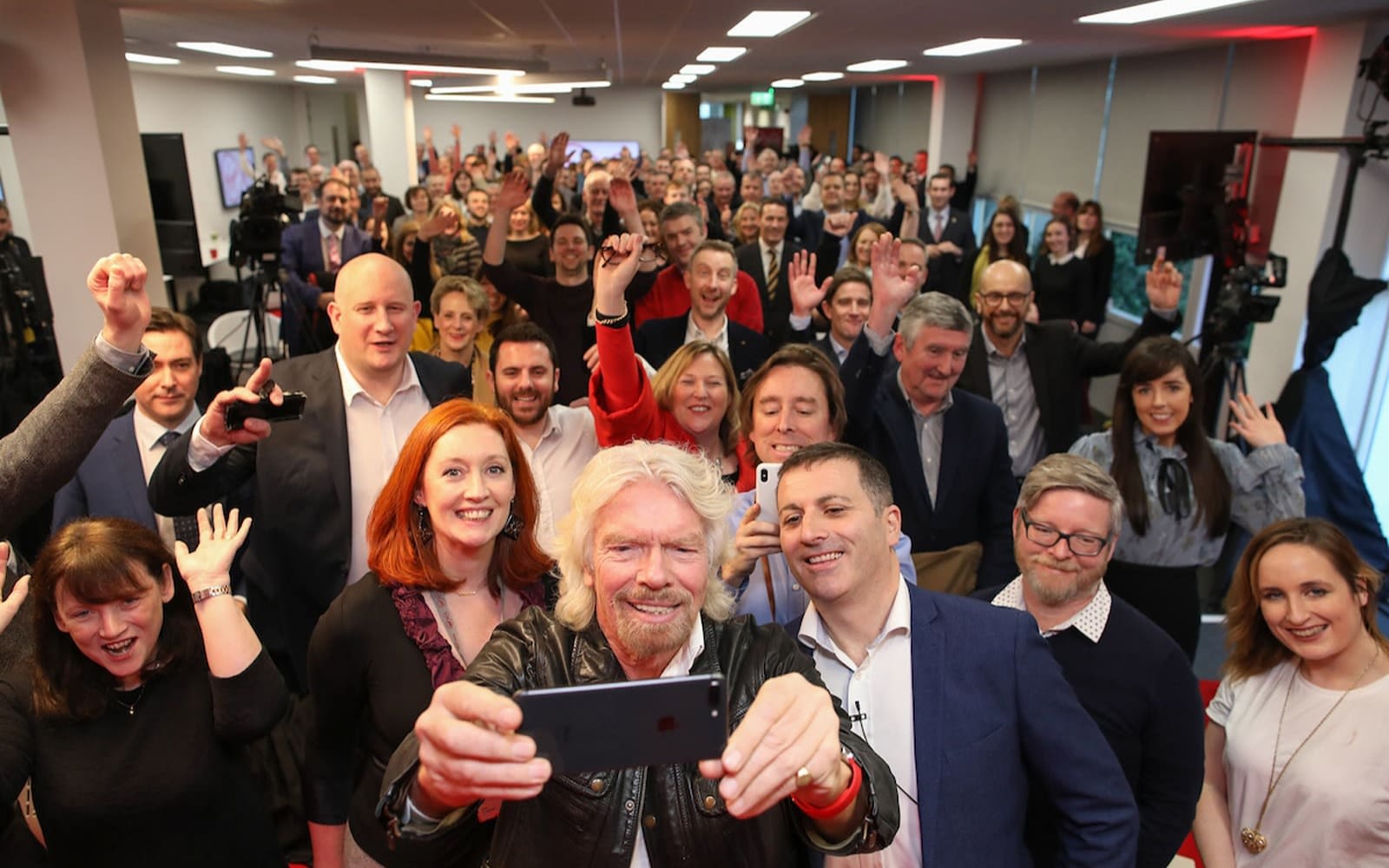 Richard Branson takes a selfie on an iPhone with the Virgin Media Ireland team
