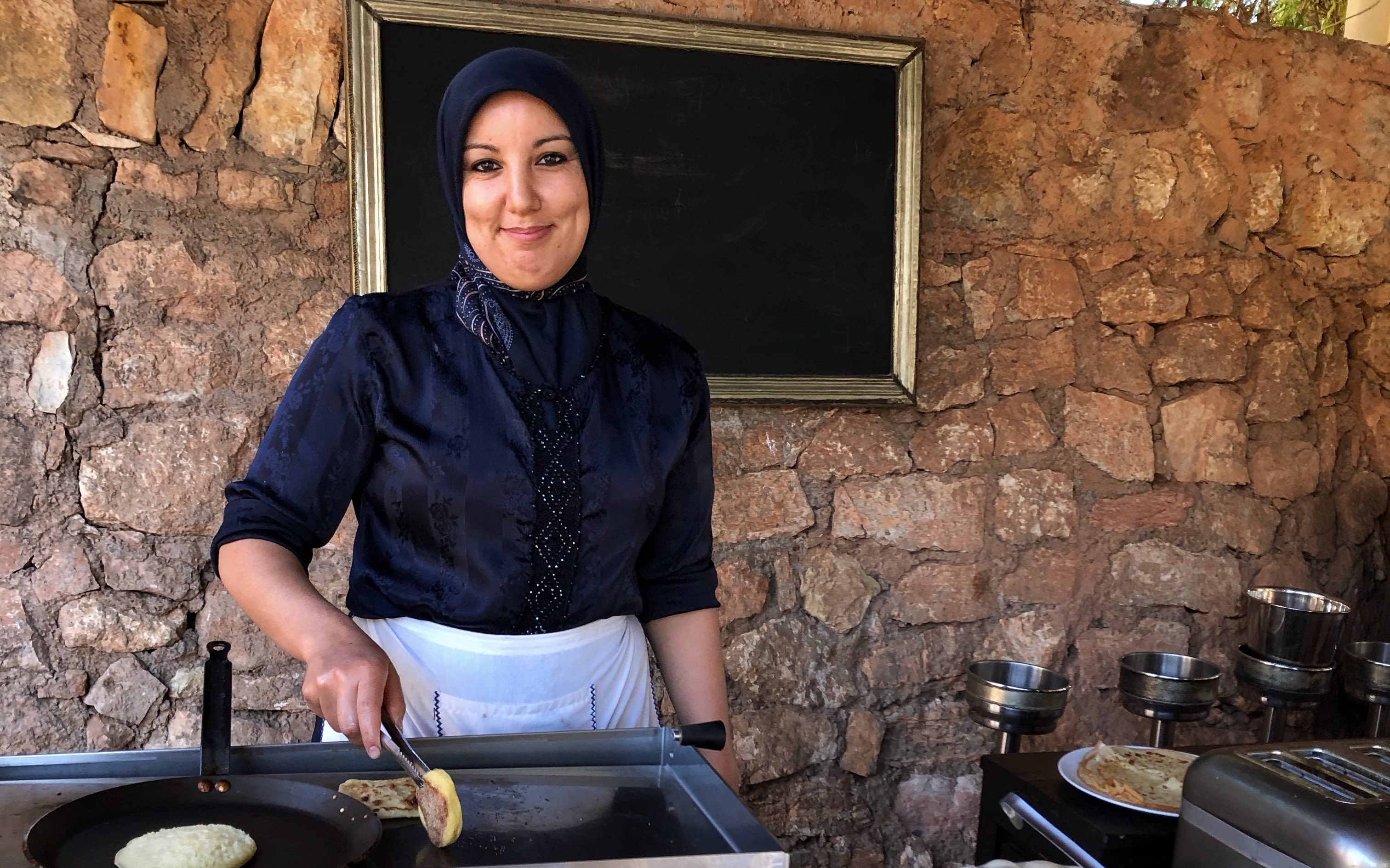 A smiling woman serves breakfast at Kasbah Tamadot in Morocco