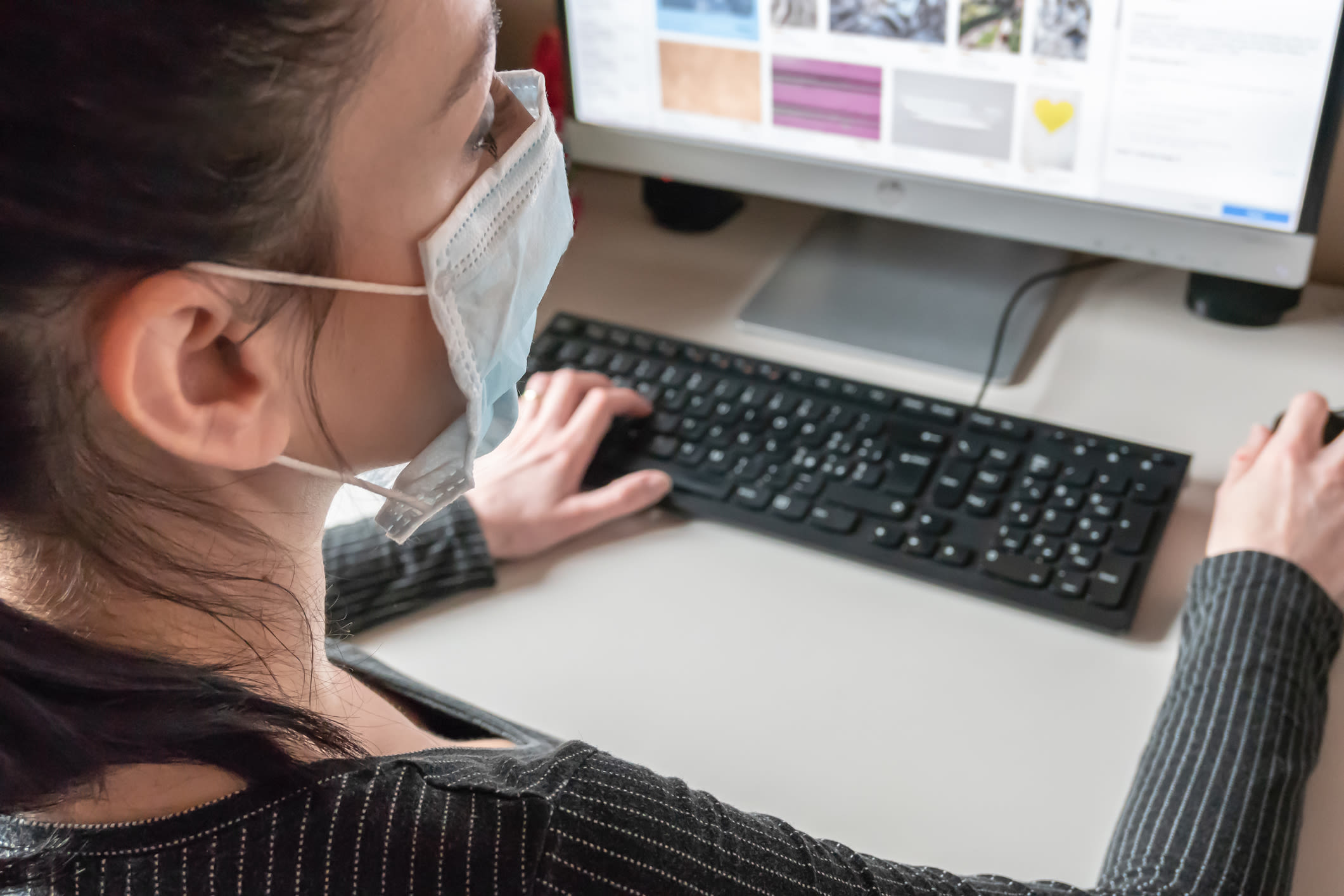 A woman wearing a mask at her desk