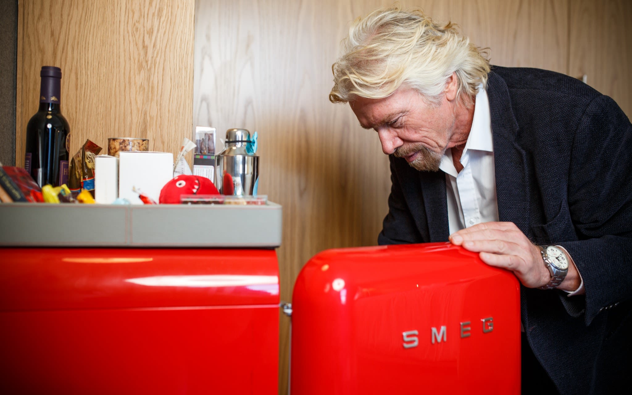 Richard Branson looking in the red Smeg mini fridge in one of the Virgin Hotels rooms